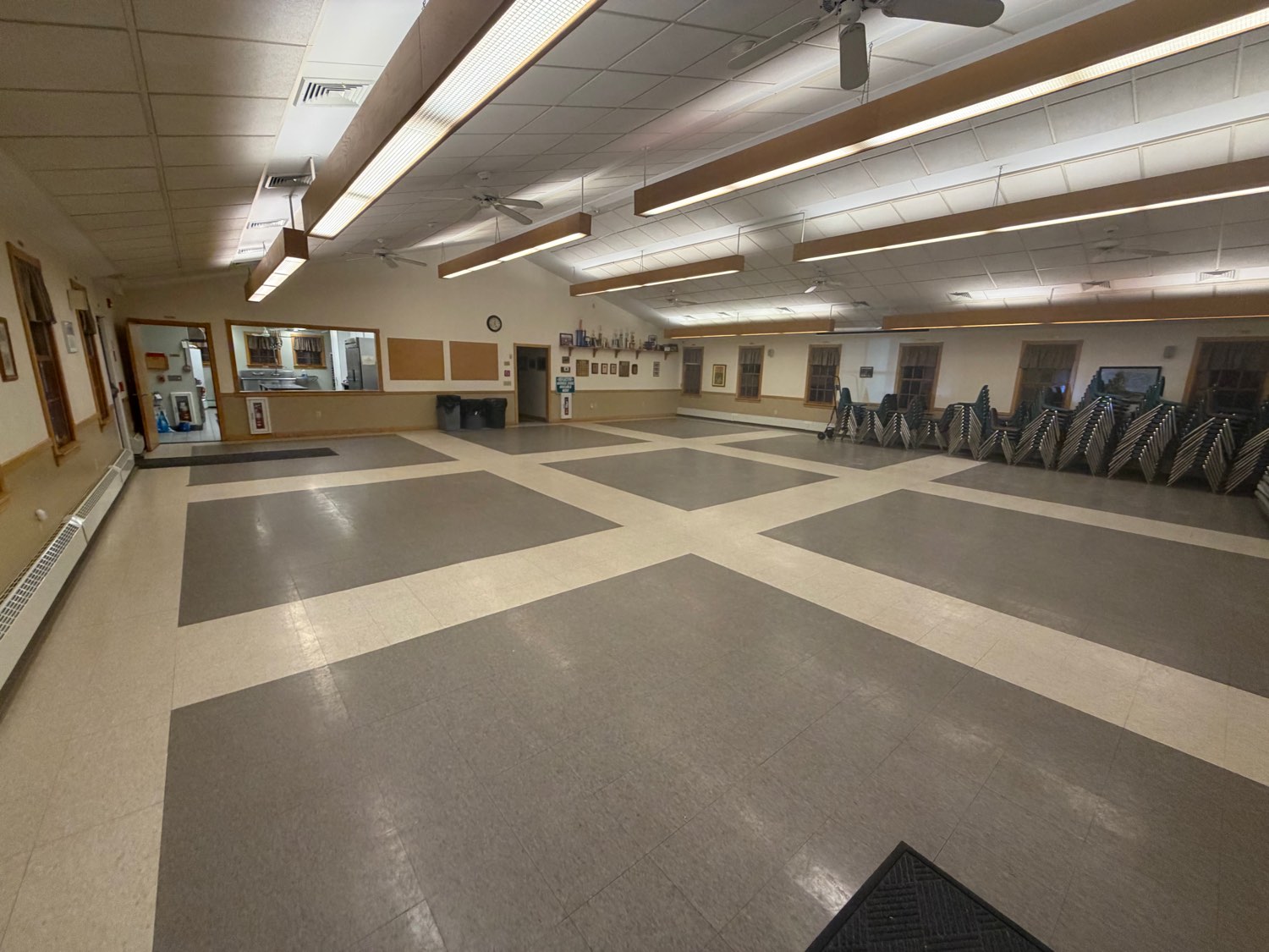 The open main hall, with the kitchen pass-through window and stacked tables and chairs along the wall.